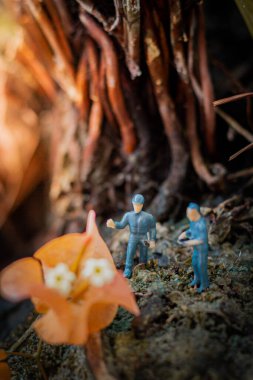 Minyatür insanlar: Küçük kaşifler tropikal ormandaki büyük çiçekleri inceliyorlar. (Daha iyi bir dünya için ağaç dikiyoruz)