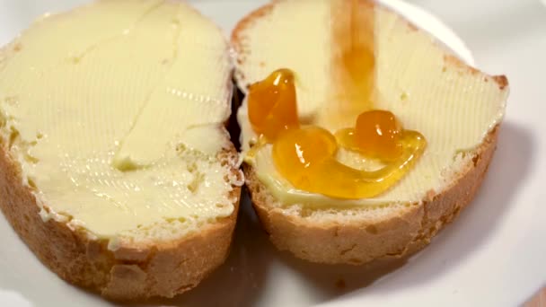 Engarrafamento em sanduíches. Café da manhã preparando com manteiga e geléia espalhados sobre o pão — Vídeo de Stock