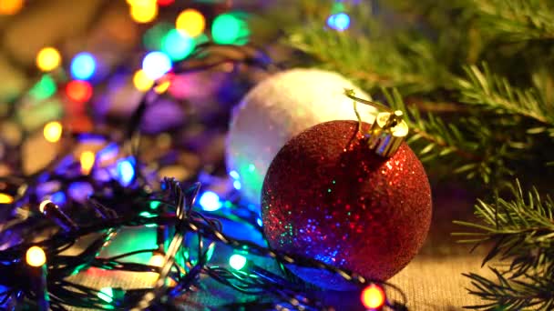 Red, White Balls, Pine Branches and Garlands of Multicolored LED Lamps Lie on a Table Close-up Різдвяні свята і різдвяна підготовка. — стокове відео