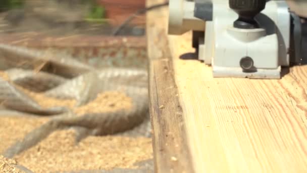 Planing an old board with an electric plane in sunlight. Refresh the wood plank surface — Stock Video