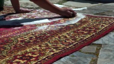 Bir kadın evin avlusunda, caddede kirli bir halıyı fırçalıyor. Temiz suyla çalkala. Tozdan çok köpük çıkıyor. Kapalı yıkama halısı. Fırça halıyı temizler
