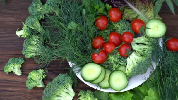 ZDRAVOTNÍ POTRAVINY. Skupina čerstvých listů salátu a syrové zeleniny na dřevěné desce — Stock video