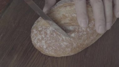 S-Log3. Koyu bir tahta üzerinde bir somun ekmek kesmek. Yakın plan. Yukarıdan görüntüle