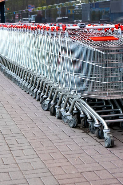 Many empty grocery carts stand in a row near the supermarket