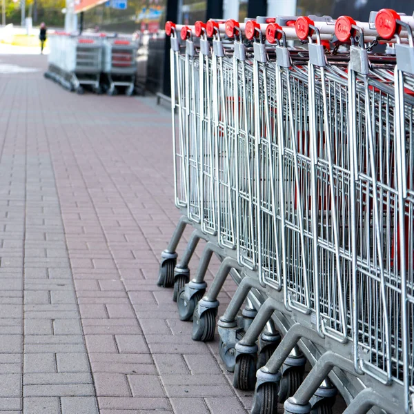 Many empty grocery carts stand in a row near the supermarket