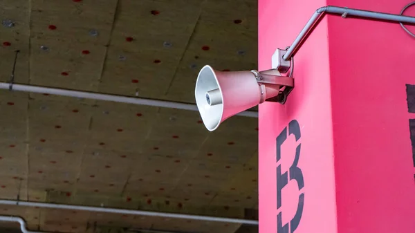 Hoparlörler sütunlardan yayın yapıyor. Bir örgüt veya topluluğu bilgilendirmek için binanın tavanının altındaki beton direklere monte edilmiş. Alışveriş merkezinin altındaki yeraltı otoparkı..