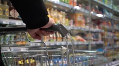 Süper Markette Ürünler Satın Almak. Yavaş bir hareket yap. Dükkanda hareket eden boş bir el arabasının yanında. Erkek eli. Yakın plan.