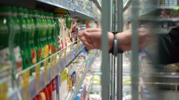 Ekaterinburg,ロシア- 2020年11月:スローモーション.商品を収集するために冷蔵庫のガラスのドアを開きます。スーパーでは:男が冷蔵庫のドアを開き、子食品を取ります。閉じる — ストック動画