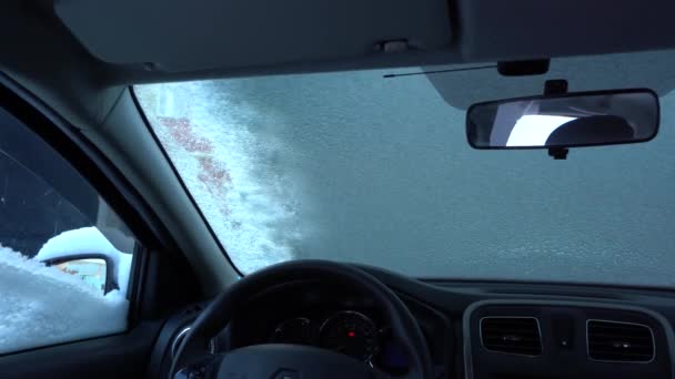 Человек очищает машину от снега, вид изнутри автомобиля — стоковое видео