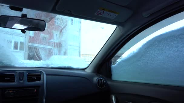Seorang pria membersihkan mobil dari salju, pemandangan dari dalam mobil — Stok Video