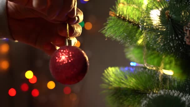 Staruszki zdobią choinkę czerwonymi świątecznymi kulkami, elektryczną girlandą błyszczy i miga w tle, tradycyjnym Nowym Rokiem i przygotowaniami świątecznymi — Wideo stockowe