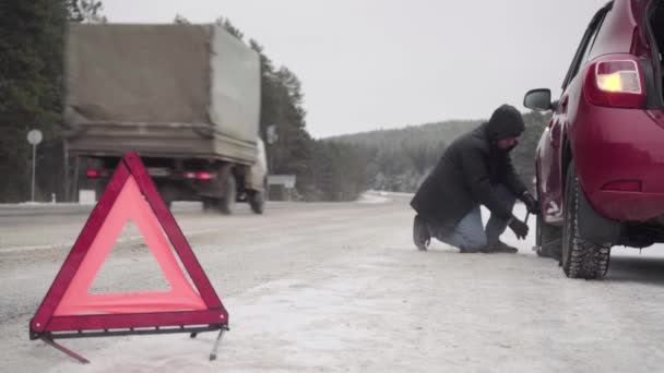 Επείγουσα στάση του αυτοκινήτου στην άκρη του δρόμου το χειμώνα. Φωτεινό κόκκινο τρίγωνο σε χιονισμένο δρόμο προειδοποιεί άλλους οδηγούς — Αρχείο Βίντεο