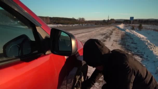 Jekaterinburg, Ryssland - november 2020: Nödstopp för bilen vid vägkanten en solig vinterdag. En man byter hjul på en bil — Stockvideo