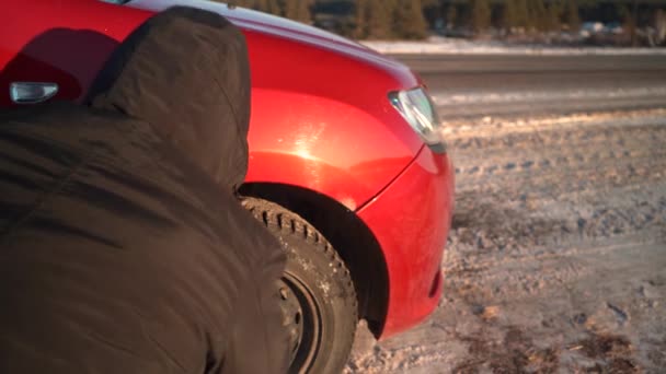 Nödstopp av bilen på vägen en solig vinterdag. En man byter hjul på en bil. — Stockvideo