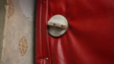 Eski kapıyı içeriden kapat. Bir adamın eli, kırmızı dermantin kaplı eski sefil bir kapıyı kapatır.