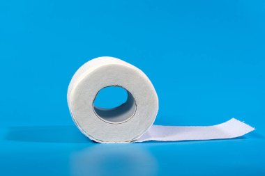 Mavi arkaplanda izole edilmiş bir tuvalet kağıdı rulosu