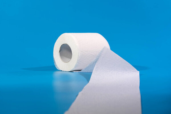 Один рулон туалетной бумаги изолирован на синем фоне