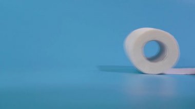 Mavi arkaplanda izole edilmiş bir tuvalet kağıdı rulosu
