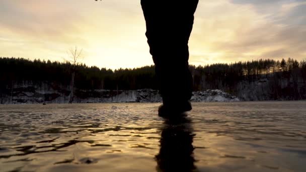 Bajo ángulo de disparo. El lago congelado. El viajero camina sobre hielo. Piernas de cerca — Vídeo de stock