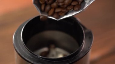 Öğütücüye kahve çekirdeği dök. Kahve çekirdeklerinin elektrikli kahve öğütücüsüne nasıl döküldüğünün makro videosu..