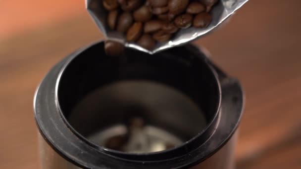 Despeje grãos de café no moedor. Vídeo macro de como os grãos de café estão derramando sobre a lâmina de um moedor de café elétrico. — Vídeo de Stock
