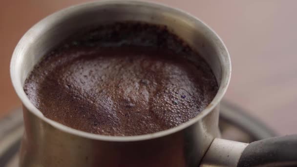 Мелену чорну каву в сталевому Турку варять і кип'ятять на плиті. Піна на поверхні крупним планом — стокове відео
