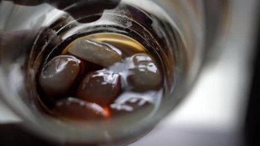 Buz küpleri bir bardağın içinde kahverengi bir içeceğin içinde yüzer. Elin buzlu bir bardak tutsun..