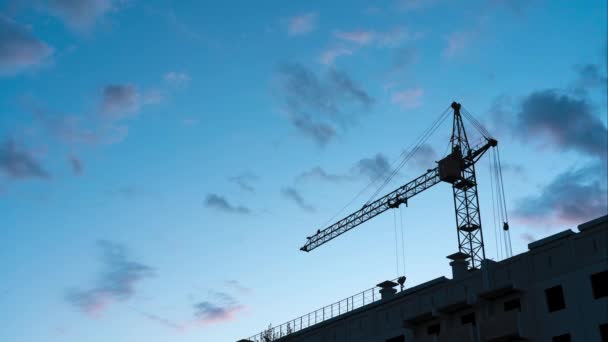 Grúa torre contra el cielo. Al anochecer, las nubes se mueven a través del cielo azul. Concepto: Construcción detenida — Vídeo de stock