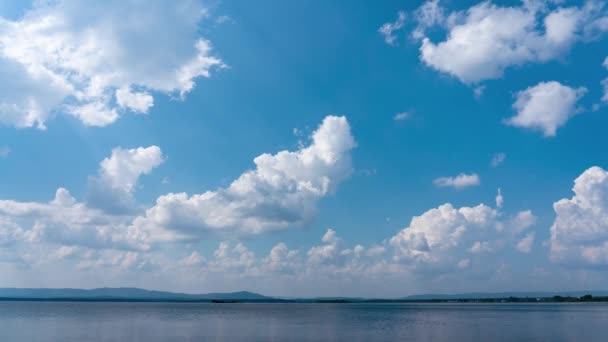 Nuvens brancas se movem rapidamente contra o céu azul em um dia de verão ensolarado brilhante sobre o lago. — Vídeo de Stock
