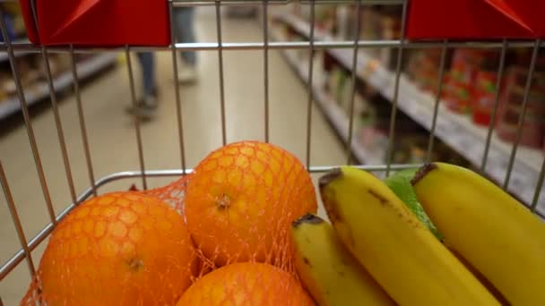 Тележка с продуктами в супермаркете движется по проходу между полками. Inside view of the cart — стоковое видео