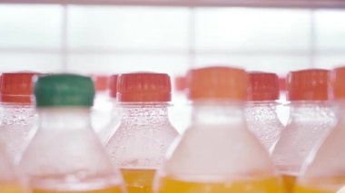 Vitrinin yanındaki dükkanda bir sürü plastik içki şişesi var. Yakından çek. Karbonatlı meşrubat şişeleri.