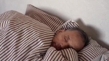 Caucasian Elderly Man Wakes Up Holding His Head Feeling Headache. Old Man in Pajamas Wakes up Feeling Bad