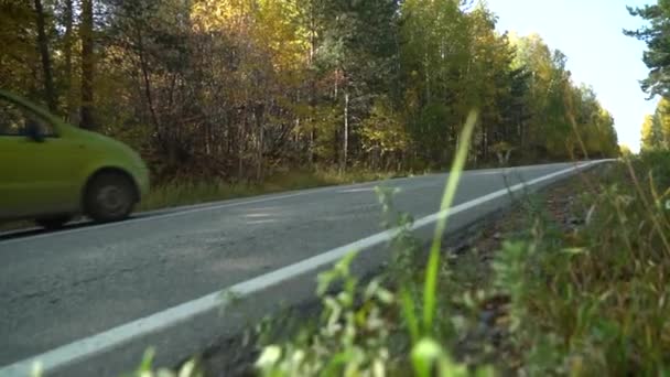 Rid uppför. En personbil kör längs vägen, går uppför, bland skogar. — Stockvideo