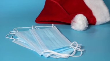 Santa Claus hat, gloves and medical mask on a blue background