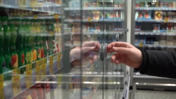 Al rallentatore. Primo piano. Dolly Shot. Porta del frigorifero di vetro di apertura della mano maschio in supermercato. La fotocamera penetra nel frigorifero — Video Stock