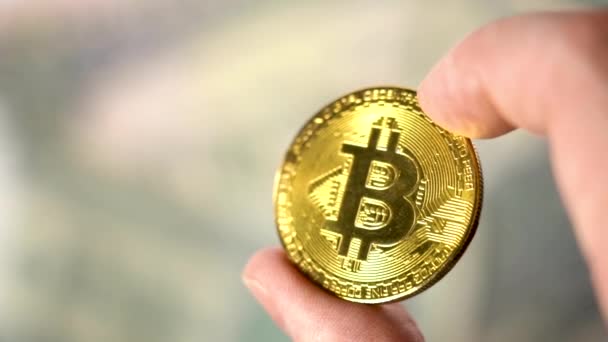 Houd Gold Bitcoin Coin op de achtergrond van dollars. Mans Fingers Holding Bitcoin gouden munten — Stockvideo