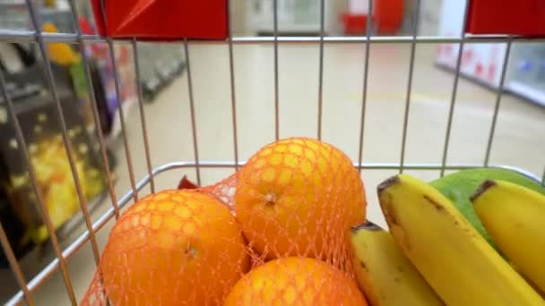 Um carrinho de supermercado num supermercado desce o corredor entre as prateleiras. Vista interior do carrinho — Vídeo de Stock