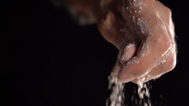 Pour Flour From a Mans Hand на черном фоне — стоковое видео