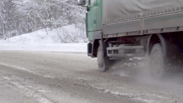 Nieve suelta vuela desde debajo de ruedas de camiones en la carretera — Vídeos de Stock