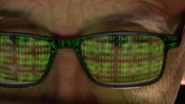 Programador con gafas delante de la pantalla. Detalle de una mirada de persona, un código de hacker se refleja en las gafas — Vídeo de stock