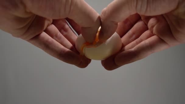 Kırık Yumurta Tutan Erkek Eller. Kupanın üstündeki yumurtayı kır. Mavi Arkaplan. Yavaş Hareket — Stok video