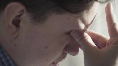 Yorgun adam gözlerini ovuşturuyor. Yakın plan..