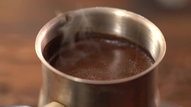 Caffè nero macinato in un turco d'acciaio viene prodotta e bollita sulla stufa. Schiuma sulla superficie primo piano — Video Stock