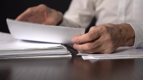 Крупным планом. Замедление. Куча деловых бумаг на столе. пожилой человек держит лист бумаги — стоковое видео