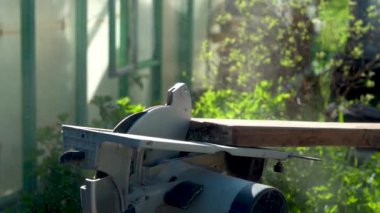 Dairesel testere ile ahşap bir tahta gördüm. Bir kır evinde güpegündüz tahta testereyle kesme sürecinin yakın çekimi..