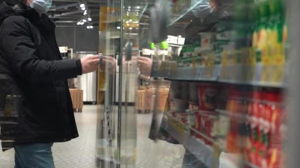 Truck Shot. Slow Motion. A Man in a Medical Mask Takes A Product From A Refrigerated Shelf in a Supermarket — Stock Video