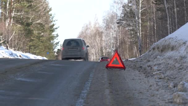 Vörös figyelmeztető háromszög egy téli úton az erdőben. Trouble Utazás autóval télen — Stock videók