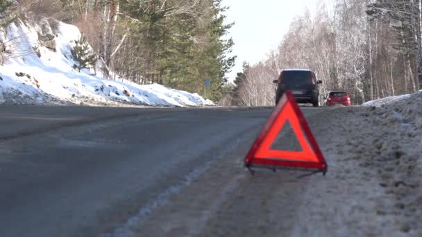 Red Warning Triangle em uma estrada de inverno na floresta. Problemas em viajar de carro no inverno — Vídeo de Stock
