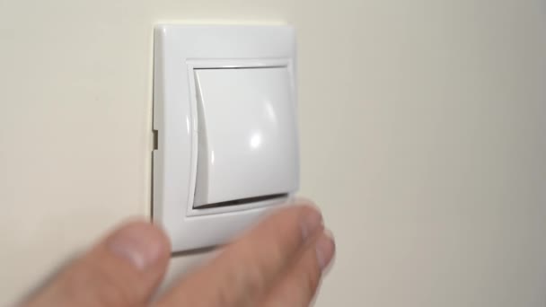 Spegnimento illuminazione elettrica. La mano di un anziano spegne la luce con un interruttore a muro — Video Stock
