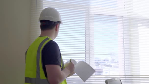 Un trabajador con casco lleva registros. Un capataz escribe en un diario. Ingeniero de Construcción Masculino Con Proyecto de Construcción en Papel, Hombre en Ropa Formal y Casco Controla el Trabajo — Vídeos de Stock